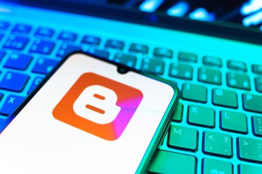 Prag, Çek Cumhuriyeti - 08 19 2025: Klavyenin üzerinde duran ve Blogger logosunu gösteren cep telefonunun yakından görüntüsü. Blogger blog oluşturma ve yayınlama için bir platformdur.