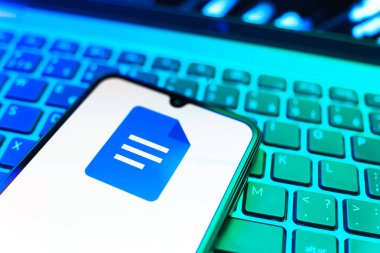Prag, Çek Cumhuriyeti - 08 19 2025: Google Docs logosunu gösteren klavyenin üzerinde duran cep telefonunun yakından görüntüsü. Google Docs metin belgeleri oluşturmak ve düzenlemek için bir platformdur.