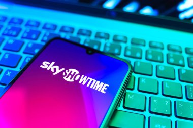 Prag, Çek Cumhuriyeti - 08 19 2025: SkyShowtime logosunu gösteren klavyenin üzerinde duran cep telefonunun yakından görüntüsü. SkyShowtime, sinema ve televizyon dizileri için bir yayın platformudur..