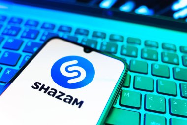 Prag, Çek Cumhuriyeti - 08 19 2025: Klavyede duran ve Shazam logosunu gösteren bir cep telefonunun yakından görüntüsü. Shazam şarkıları ve müzik parçalarını tanımlamak için bir uygulamadır.