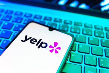 Prag, Çek Cumhuriyeti - 08 19 2025: Klavyede duran ve Yelp logosunu gösteren bir cep telefonunun yakından görüntüsü. Yelp yerel işletmeleri bulmak ve incelemek için bir platformdur.