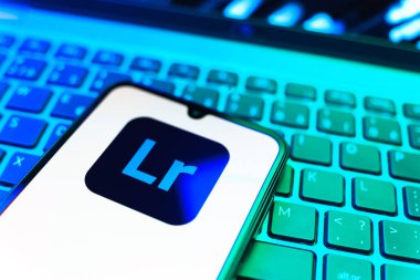 Prag, Çek Cumhuriyeti - 08 19 2025: Klavyede duran ve Lightroom logosunu gösteren cep telefonunun yakından görüntüsü. Lightroom fotoğraf düzenleme ve yönetim için bir yazılımdır..