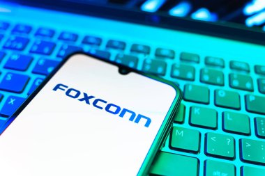 Prag, Çek Cumhuriyeti - 08 19 2025: Foxconn logosunu gösteren klavyenin üzerinde duran cep telefonunun yakından görüntüsü. Foxconn elektronik ve parça üreten bir şirket..