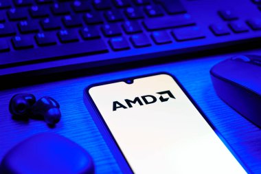 Prag, Çek Cumhuriyeti - 08 12 2025: AMD logosunu gösteren klavyesi ve cep telefonu olan bir masanın yan görüntüsü. AMD, işlemci ve işlemci üreten yarı iletken bir şirkettir..