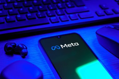 Prague, Czechia - 08 12 2025: A side view of a desk with a keyboard and a mobile phone displaying the Meta logo. Meta is a company offering social platforms like Facebook and Instagram.