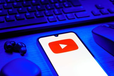 Prague, Czechia - 08 12 2025: A side view of a desk with a keyboard and a mobile phone displaying the Youtube logo. Youtube is a platform to watch and share videos worldwide.