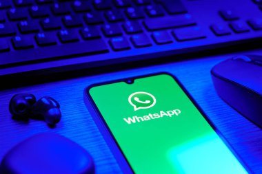 Prague, Czechia - 08 12 2025: A side view of a desk with a keyboard and a mobile phone displaying the WhatsApp logo. WhatsApp is an app for sending texts, calls, and media.