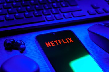 Prague, Czechia - 08 12 2025: A side view of a desk with a keyboard and a mobile phone displaying the Netflix logo. Netflix is a streaming platform for movies and TV shows.