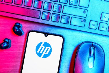 Prague, Czechia - 08 09 2025: A top-down view of a desk with a phone displaying the Hewlett-Packard logo. Hewlett-Packard is a technology company producing computers and printers.