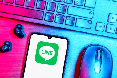 Prague, Czechia - 08 09 2025: A top-down view of a desk with a phone displaying the Line logo. Line is a messaging app for calls, texts, and multimedia sharing.