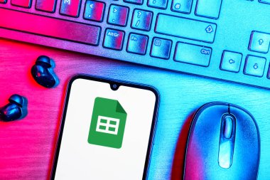 Prague, Czechia - 08 09 2025: A top-down view of a desk with a phone displaying the Google Sheets logo. Google Sheets is a platform for creating and managing spreadsheets.
