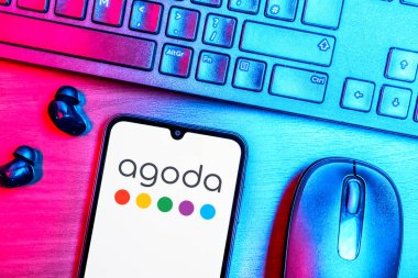 Prague, Czechia - 08 09 2025: A top-down view of a desk with a phone displaying the Agoda logo. Agoda is a platform for booking hotels and travel accommodations.
