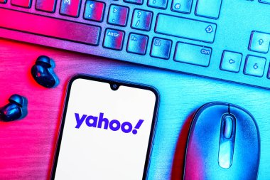 Prague, Czechia - 08 09 2025: A top-down view of a desk with a phone displaying the Yahoo logo. Yahoo is a platform for news, email, and online services.