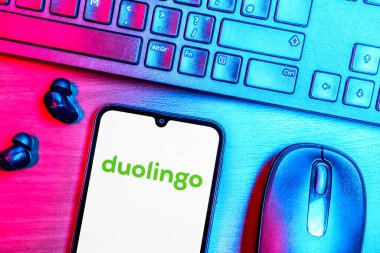 Prague, Czechia - 08 09 2025: A top-down view of a desk with a phone displaying the Duolingo logo. Duolingo is a platform for learning languages interactively.