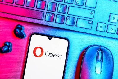 Prague, Czechia - 08 09 2025: A top-down view of a desk with a phone displaying the Opera logo. Opera is a web browser for fast and secure internet browsing.