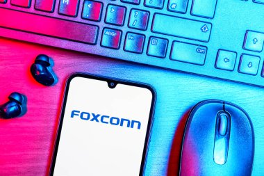 Prague, Czechia - 08 09 2025: A top-down view of a desk with a phone displaying the Foxconn logo. Foxconn is a company manufacturing electronics and components.
