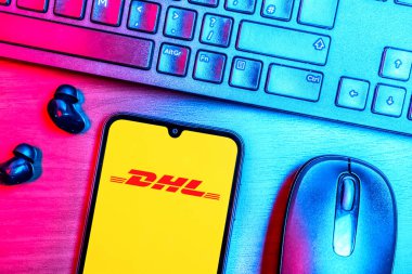 Prague, Czechia - 08 09 2025: A top-down view of a desk with a phone displaying the DHL logo. DHL is a logistics company offering international shipping services.