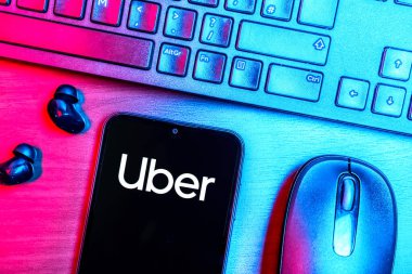 Prague, Czechia - 08 09 2025: A top-down view of a desk with a phone displaying the Uber logo. Uber is a ride-hailing app for transportation and delivery services.
