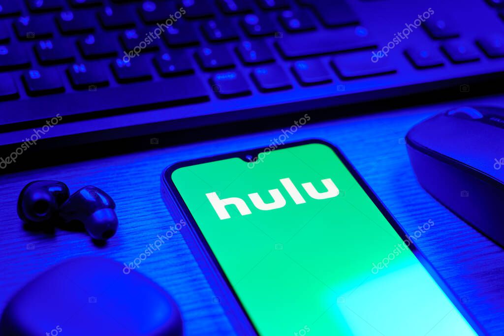 Prague, Czechia - 08 12 2025: A side view of a desk with a keyboard and a mobile phone displaying the Hulu logo. Hulu is a streaming platform for TV shows, movies, and live TV.