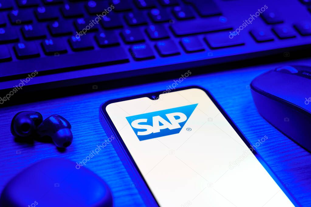 Prague, Czechia - 08 12 2025: A side view of a desk with a keyboard and a mobile phone displaying the SAP logo. SAP is a software company providing enterprise applications and solutions.