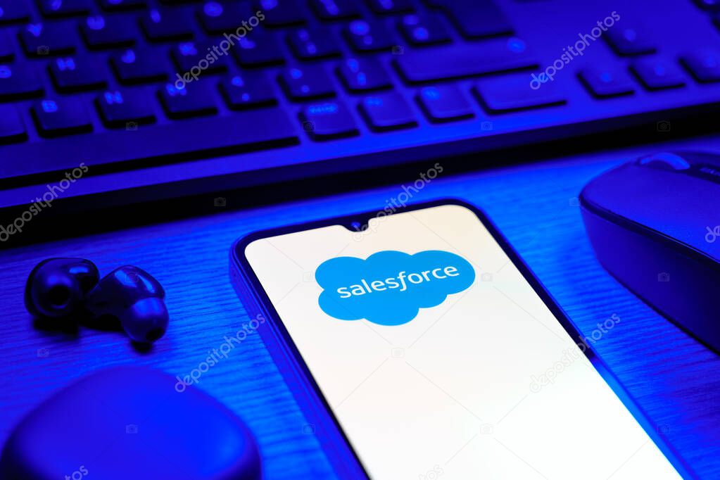 Prague, Czechia - 08 12 2025: A side view of a desk with a keyboard and a mobile phone displaying the Salesforce logo. Salesforce is a platform for customer relationship management and cloud services.