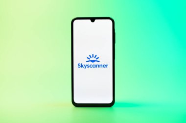 Prag, Çek Cumhuriyeti - 08 10 2025: Tek kullanımlık arka planda duran bir cep telefonu Skyscanner logosunu gösteriyor. Skyscanner uçak, otel ve araba kiralama araçlarını karşılaştırmak için bir platform..