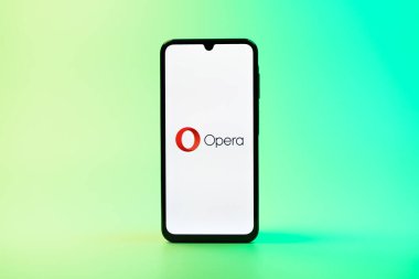 Prag, Çek Cumhuriyeti - 08 10 2025: Üniformalı arka planda duran bir cep telefonu Opera logosunu gösteriyor. Opera hızlı ve güvenli internet taraması için bir web tarayıcısıdır.