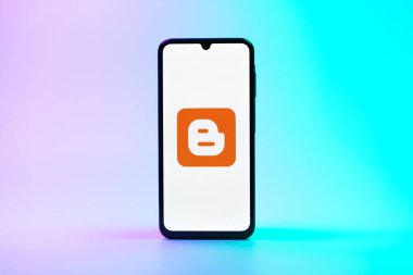 Prag, Çek Cumhuriyeti - 08 10 2025: Tek bir arkaplanda duran bir cep telefonu Blogger logosunu gösterir. Blogger blog oluşturma ve yayınlama için bir platformdur.