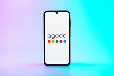 Prag, Çek Cumhuriyeti - 08 10 2025: Arka planda duran bir cep telefonu Agoda logosunu gösteriyor. Agoda, otelleri ve seyahat yerlerini ayırtmak için bir platform..