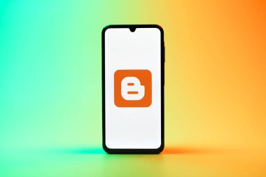 Prag, Çek Cumhuriyeti - 08 10 2025: Tek bir arkaplanda duran bir cep telefonu Blogger logosunu gösterir. Blogger blog oluşturma ve yayınlama için bir platformdur.