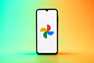 Prag, Çek Cumhuriyeti - 08 10 2025: Tek tip arka planda duran bir cep telefonu Google Photos logosunu görüntüler. Google Fotoğrafları fotoğraf ve videoları saklamak ve düzenlemek için bir platformdur.