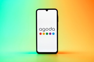Prag, Çek Cumhuriyeti - 08 10 2025: Arka planda duran bir cep telefonu Agoda logosunu gösteriyor. Agoda, otelleri ve seyahat yerlerini ayırtmak için bir platform..
