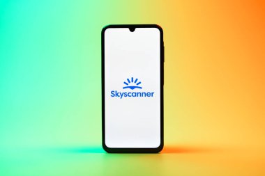 Prag, Çek Cumhuriyeti - 08 10 2025: Tek kullanımlık arka planda duran bir cep telefonu Skyscanner logosunu gösteriyor. Skyscanner uçak, otel ve araba kiralama araçlarını karşılaştırmak için bir platform..
