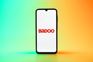 Prag, Çek Cumhuriyeti - 08 10 2025: Üniformalı arka planda duran bir cep telefonu Badoo logosunu gösteriyor. Badoo insanlarla tanışmak ve iletişim kurmak için bir randevu uygulaması..