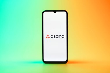 Prag, Çek Cumhuriyeti - 08 10 2025: Arka planda duran bir cep telefonu Asana logosunu gösteriyor. Asana görev yönetimi ve takım işbirliği için bir platformdur..
