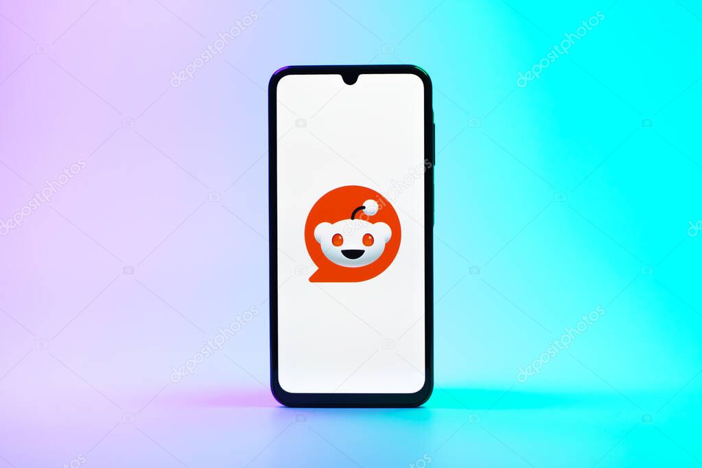 Prague, Czechia - 08 10 2025: A mobile phone standing on a uniform background displays the Reddit logo. Reddit is a platform for discussion, news, and community content.
