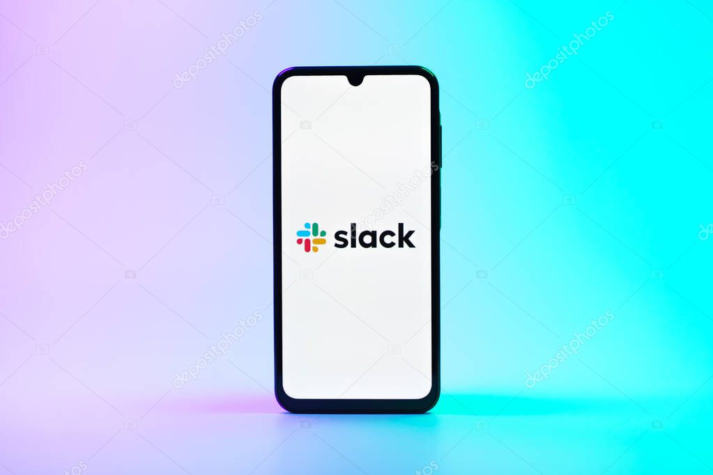 Prague, Czechia - 08 10 2025: A mobile phone standing on a uniform background displays the Slack logo. Slack is a platform for team messaging and workplace communication.