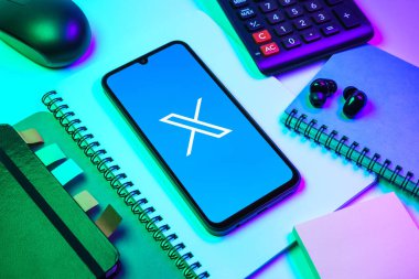 Prag, Çek Cumhuriyeti - 08 18 2025: Merkezinde X logosu sergilenen bir cep telefonu ile ofis malzemeleri düzenlemesi. X, kısa gönderileri ve güncellemeleri paylaşmak için bir platformdur.