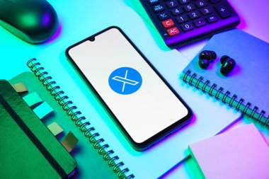 Prag, Çek Cumhuriyeti - 08 18 2025: Merkezinde X logosu sergilenen bir cep telefonu ile ofis malzemeleri düzenlemesi. X, kısa gönderileri ve güncellemeleri paylaşmak için bir platformdur.