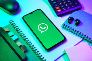 Prag, Çek Cumhuriyeti - 08 18 2025: Ofis malzemelerinin merkezde WhatsApp logosunu gösteren bir cep telefonu ile düzenlenmesi. WhatsApp mesaj, çağrı ve medya göndermek için bir uygulamadır.