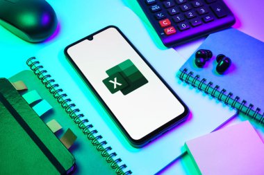 Prag, Çek Cumhuriyeti - 08 18 2025: Excel logosu sergilenen bir cep telefonu ile ofis malzemeleri düzenlemesi. Excel, tablo, veri analizi ve hesaplamalar için bir yazılımdır..