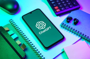 Prag, Çek Cumhuriyeti - 08 18 2025: Merkezinde ChatGPT logosu bulunan bir cep telefonu ile ofis malzemeleri düzenlemesi. ChatGPT metin üretmek ve soruları cevaplamak için bir yapay zeka sohbet robotudur..