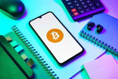 Prag, Çek Cumhuriyeti - 08 18 2025: Merkezde Bitcoin logosu sergilenen bir cep telefonu ile ofis malzemeleri düzenlemesi. Bitcoin merkezi olmayan işlemler için dijital bir kripto para birimidir.