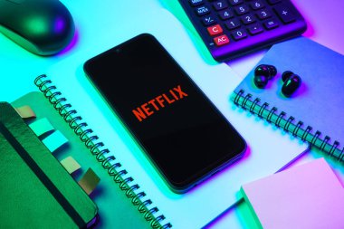 Prag, Çek Cumhuriyeti - 08 18 2025: Merkezde Netflix logosunu gösteren bir cep telefonu ile ofis malzemeleri düzenlemesi. Netflix sinema ve televizyon programları için bir yayın platformudur..