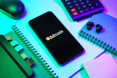 Prag, Çek Cumhuriyeti - 08 18 2025: Merkezde Bitcoin logosu sergilenen bir cep telefonu ile ofis malzemeleri düzenlemesi. Bitcoin merkezi olmayan işlemler için dijital bir kripto para birimidir.