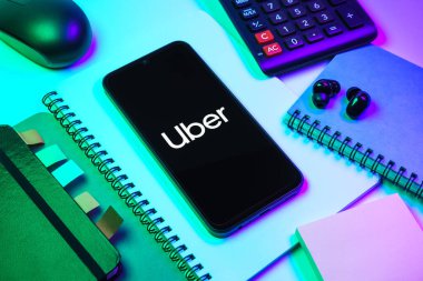 Prag, Çek Cumhuriyeti - 08 18 2025: Merkezde Uber logosu gösteren bir cep telefonu ile ofis malzemeleri düzenlemesi. Uber ulaşım ve dağıtım hizmetleri için bir gezinti selamlama uygulaması.