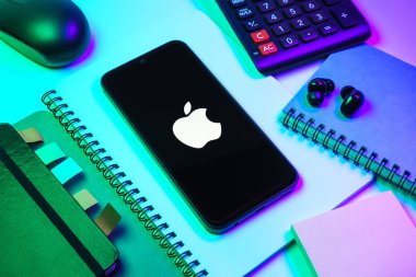 Prag, Çek Cumhuriyeti - 08 18 2025: Merkezi Apple logosunu gösteren bir cep telefonu ile ofis malzemeleri düzenlemesi. Apple iPhone, bilgisayar ve hizmet üreten bir teknoloji şirketidir..