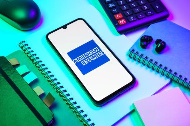Prag, Çek Cumhuriyeti - 08 18 2025: Merkezde American Express logosunu gösteren bir cep telefonu ile ofis malzemeleri düzenlemesi. American Express kart ve bankacılık sunan bir finans şirketidir..