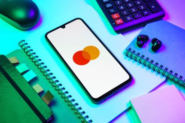 Prag, Çek Cumhuriyeti - 08 18 2025: Merkezde Mastercard logosu sergilenen bir cep telefonu ile ofis malzemeleri düzenlemesi. Mastercard ödeme kartları ve hizmetler sağlayan bir finans şirketidir..