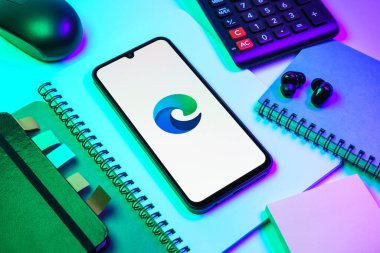 Prag, Çek Cumhuriyeti - 08 18 2025: Merkezde Edge logosunu gösteren bir cep telefonu ile ofis malzemeleri düzenlemesi. Edge, Microsoft tarafından Windows aygıtları için geliştirilen bir web tarayıcısıdır..